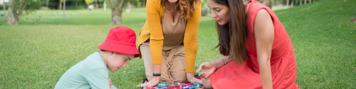 A child and two women enjoying a drawing session on a picnic blanket in a park in Portugal.